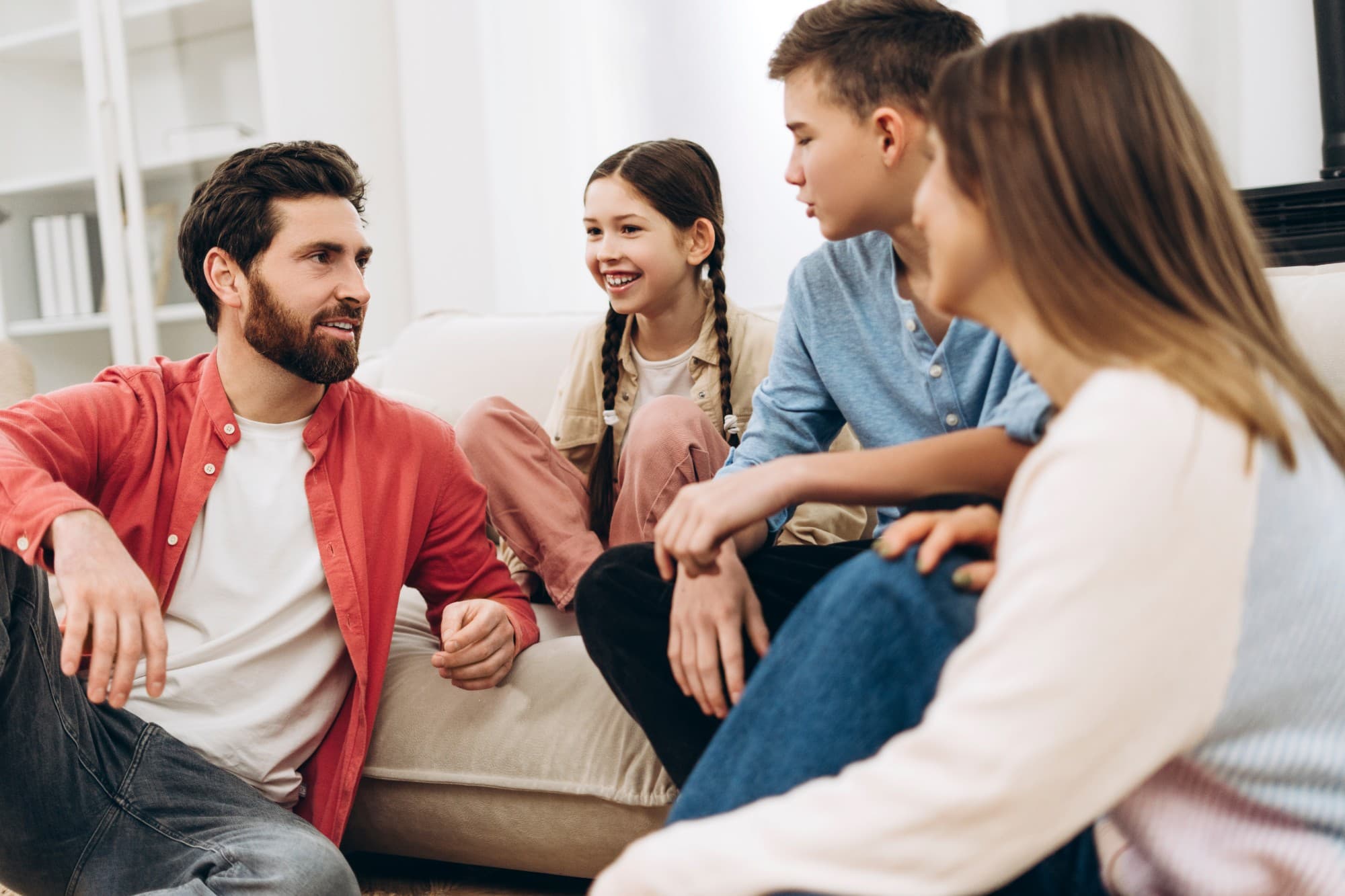 Family of four talking together in a bright living room